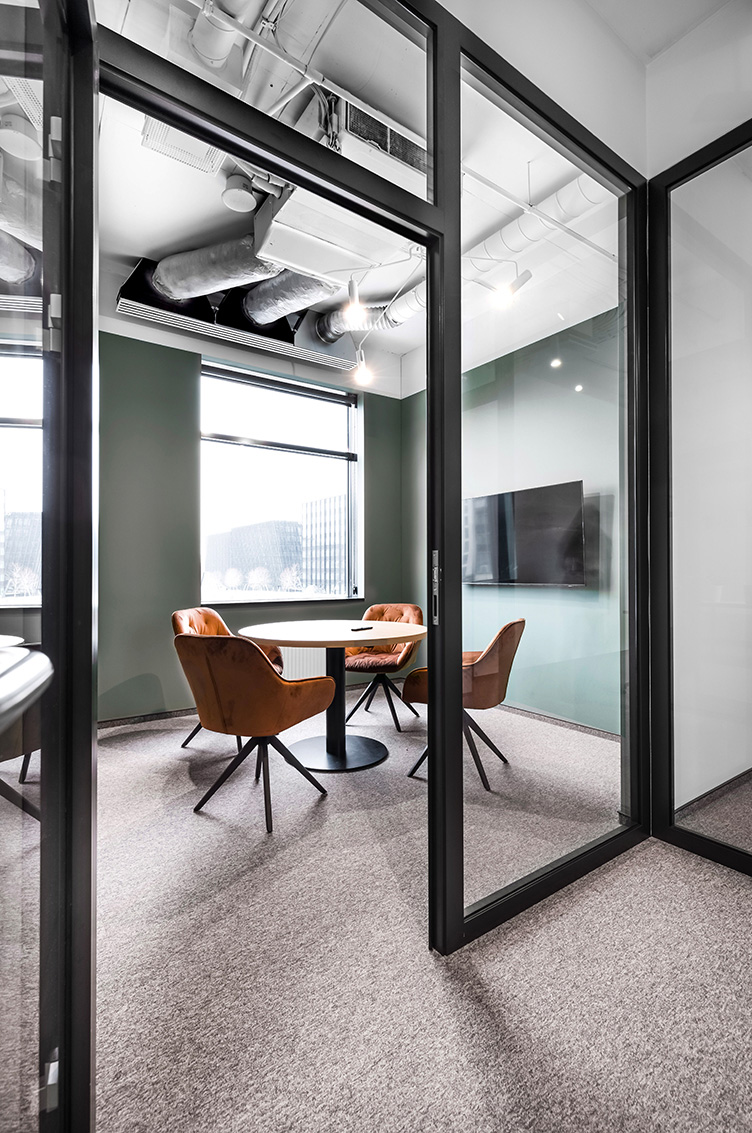 rudas kilimas pasitarimų kambaryje ir oranžinės aksominės kėdės