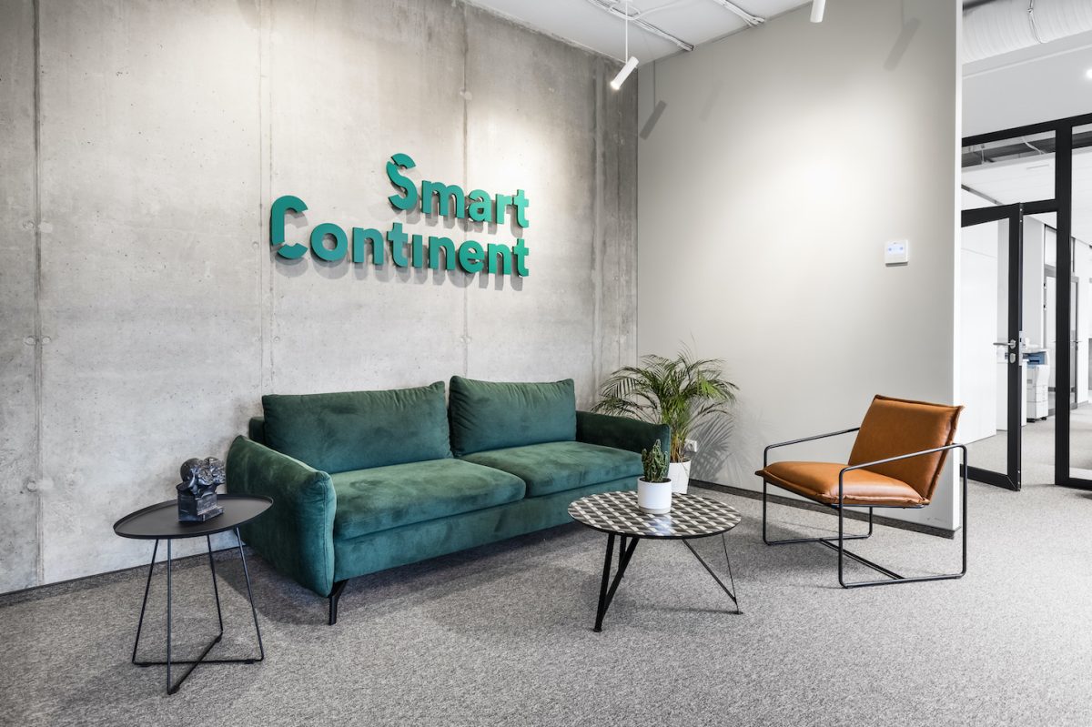 biuro interjeras su žalia sofa ir betono siena