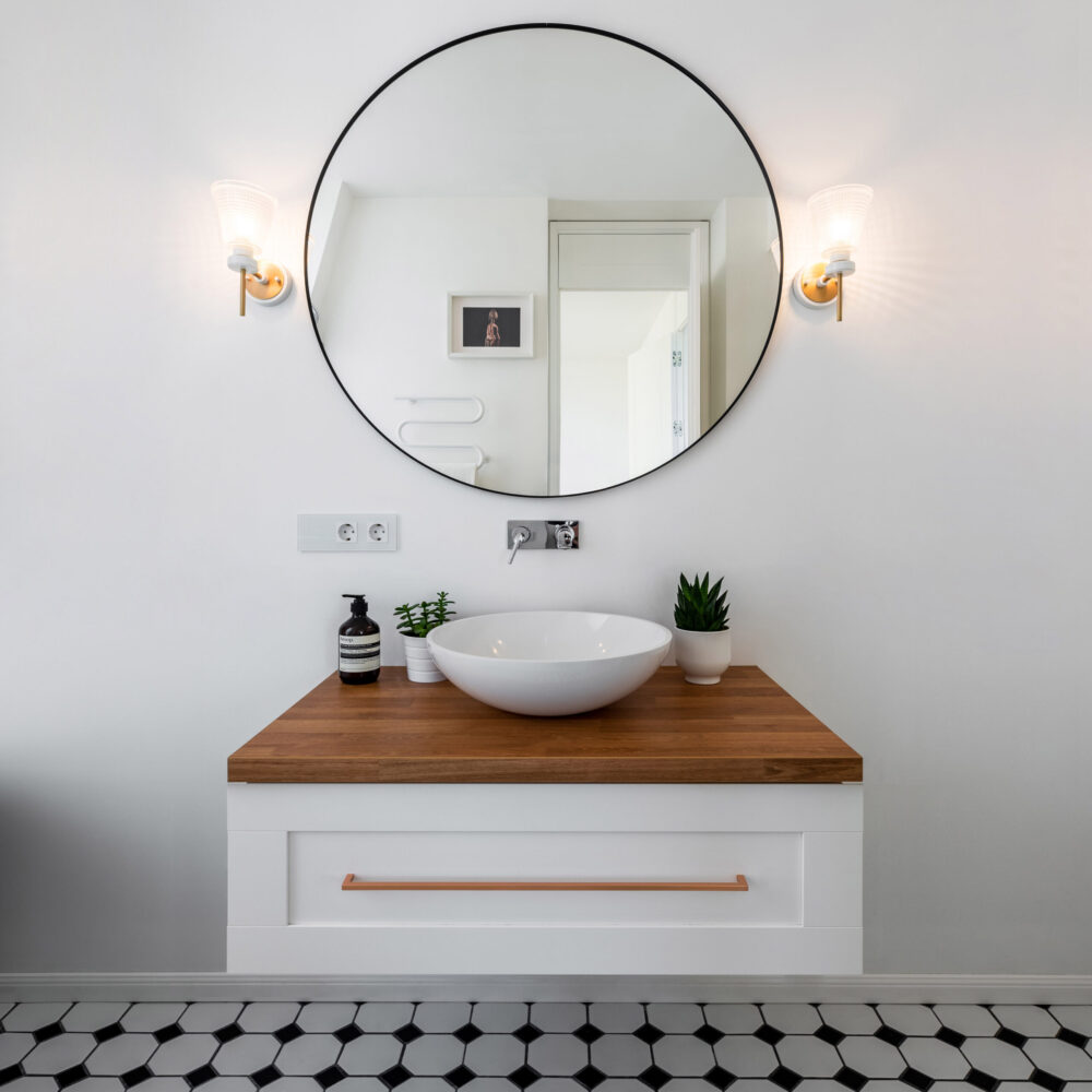 pakabinama vonios spintelė su pastatomu praustuvu ir apvaliu veidrodžiu