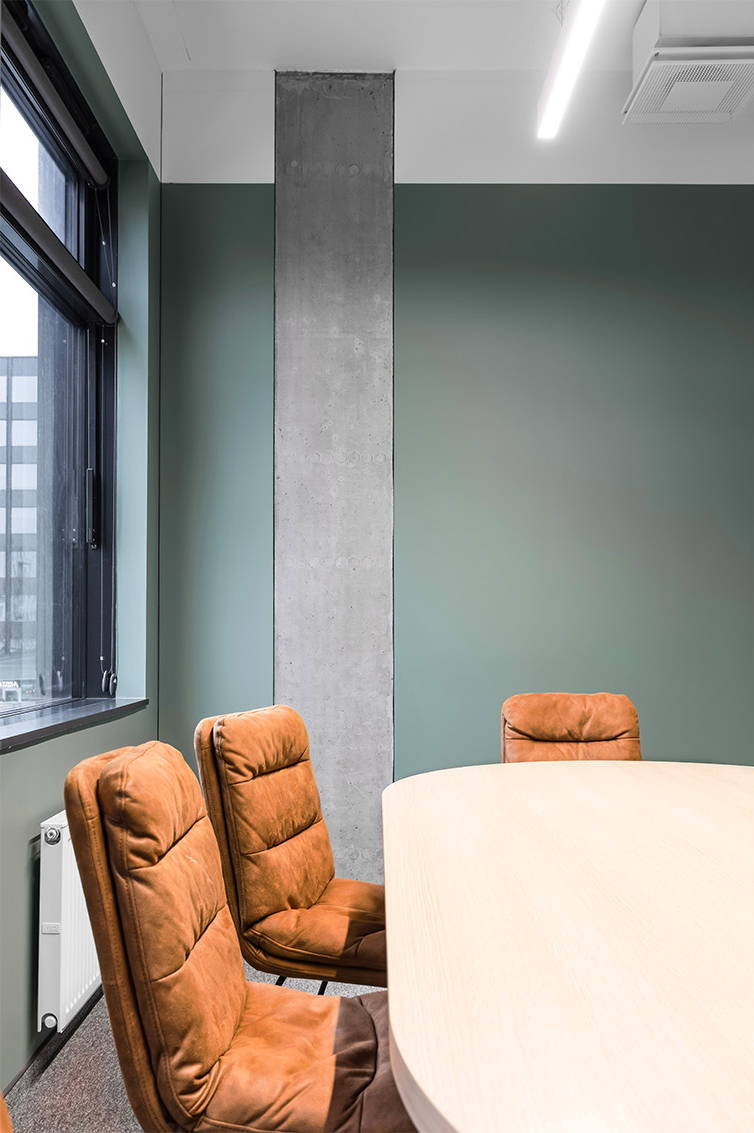 ruda odinė kėdė ir tamsiai žalias biuro interjeras