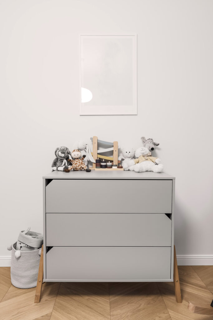 pilka komoda vaikų kambaryje su žaislais