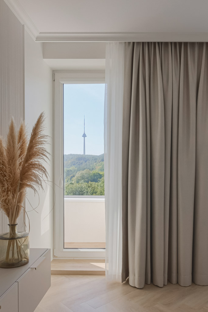 Modernios klasikos, pastelinių atspalvių svetainė ir vaizdas į televizijos bokštą