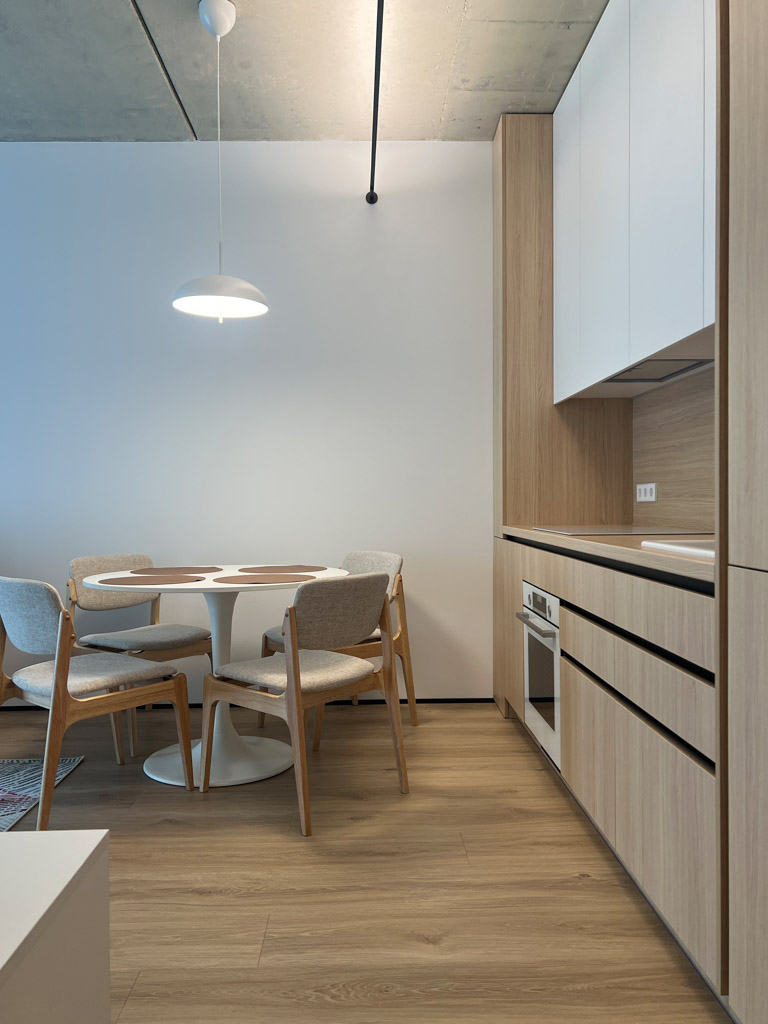 modernus valgomojo interjeras su šviesiomis kėdėmis ir medžio virtuve