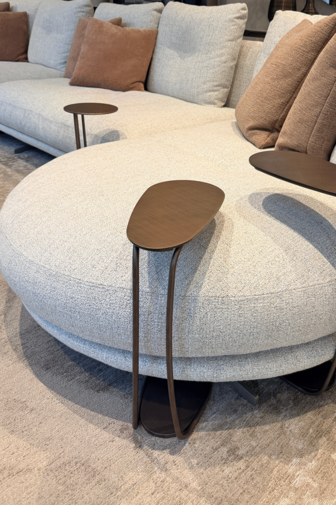 Pilka sofa su bronzos spalvos staliukais